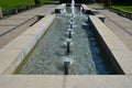 Swimming pool with fountains in the shape of an opposite cross on the promenade in the park on the square. lined with light granit