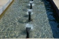 Swimming pool with fountains in the shape of an opposite cross on the promenade in the park on the square. lined with light granit