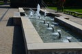 Swimming pool with fountains in the shape of an opposite cross on the promenade in the park on the square. lined with light granit