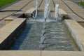 Swimming pool with fountains in the shape of an opposite cross on the promenade in the park on the square. lined with light granit