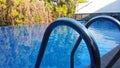 A swimming pool handrail with the reflection if trees on the surface of the swimmming pool Royalty Free Stock Photo