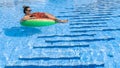 Swimming pool holidays. Happy young sexy girl in bikini swimsuit, sunglasses and inflatable rubber ring swimming in blue Royalty Free Stock Photo