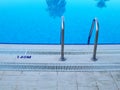 Swimming pool in-pool ladder and water depth marker Royalty Free Stock Photo