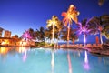 Swimming pool with palm trees at night time Royalty Free Stock Photo