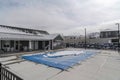 Swimming pool with plastic cover against snowy building houses and mountain Royalty Free Stock Photo