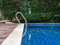 Swimming pool and stainless steel ladder with clear blue water Royalty Free Stock Photo