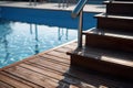 Swimming pool with stair and wooden deck at hotel. Royalty Free Stock Photo