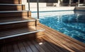 Swimming pool with stair and wooden deck at hotel. Royalty Free Stock Photo