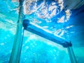 Swimming pool steps under water with light shining from the sur