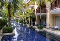 Swimming pool surrounded by a beautiful park of palm trees at the Phuket Graceland resort and spa hotel in Patong Royalty Free Stock Photo