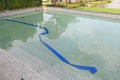 Swimming pool under maintenance with blue rubber hoses immersed. Change new water