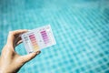 Swimming pool water testing test kit in girl hand over blurred blue swimming pool water background Royalty Free Stock Photo