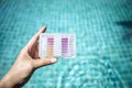 Swimming pool water testing test kit in girl hand over blurred blue water background Royalty Free Stock Photo