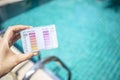 Swimming pool water testing test kit in girl hand over blurred clear blue swimming pool water Royalty Free Stock Photo