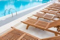 Swimming pool with wooden sunbeds. Royalty Free Stock Photo