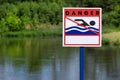 Swimming sign, on the river bank. Sign on the shore of the reservoir: swimming is prohibited. Grass and summer day. The Royalty Free Stock Photo