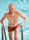 Swimming is super slimming. a happy senior man exercising in a swimming pool at a gym. Royalty Free Stock Photo