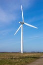 Wind turbine in fields against blue sky producing renewable energy Royalty Free Stock Photo