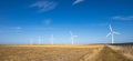 Wind turbine in fields against blue sky producing renewable energy Royalty Free Stock Photo