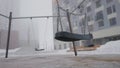 Swing on background of houses in fog. Action. Empty swing eerily seesaw on background of fog. Empty playground in cloudy