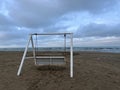 White rusty teeterboard on the shore near the sea with rocks and cloudy sky in the evening Royalty Free Stock Photo