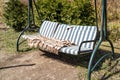 Swing bench in lush garden. Curved swing bench hanging from the bough of a tree in a lush garden with woodland backdrop Royalty Free Stock Photo