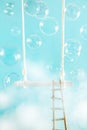 Swing with ladder and soap bubbles in the clouds on a blue background Royalty Free Stock Photo