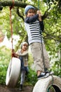 Swing life away. Shot of two cute kids playing on tire swings in their garden.