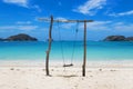 Swing made of logs on an idyllic beach of clear sand with crystal clear water on a sunny day with a blue sky. summer concept. Royalty Free Stock Photo