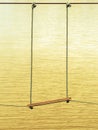 Swing made of wooden board and tied with rope hang on cable over a small stream flowing through a tropical green rainforest. Swing