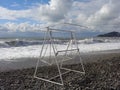 Swing on pebble beach, splashing waves and beautiful clouds Royalty Free Stock Photo