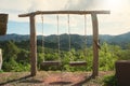 Two empty lonely hanging wooden swings on top of a hill with a beautiful view of the mountains. Royalty Free Stock Photo