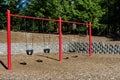 Swing set on a sunny day in a park playground, four classic black rubber swings with red posts