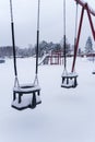 Swings covered in snow at the empty playground in winter Royalty Free Stock Photo