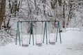 Swings in a snow covered children`s playground Royalty Free Stock Photo
