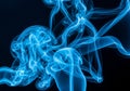 Swirling blue smoke against a black background, creating an abstract and fluid pattern. The Royalty Free Stock Photo