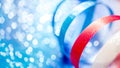 Swirling ribbons of red and white dance over backdrop of glittering blue bokeh