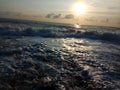 swirling waves of surf reflecting the rays of the setting evening sun.