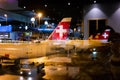 Swiss air airplane tales docked in Zurich International Airport with Swiss flag front view behind glass with reflection night time Royalty Free Stock Photo