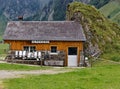 Swiss alpine cheese dairy farm built in old style next to a rock wall empty milk cans in front of the house, german alp cheese Royalty Free Stock Photo