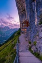 Swiss Alps and a mountain restaurant under the Aescher cliff viewed from mountain Ebenalp in the Appenzell region in Royalty Free Stock Photo