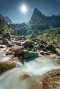 Swiss Alps of Wetterhorn peak with sunburst shine and waterfall flowing in sunny day at Reichenbach, Rosenlaui, Switzerland