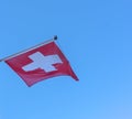 Swiss flag infront of blue sky fluttering in the wind