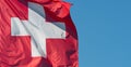 Swiss Flag. Switzerland Flag Against Blue Sky. One Red Square Flag With A White Cross In The Centre