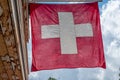 Swiss Flag. Switzerland Flag Hanging On Roof Against Blue Sky. One Red Square Flag With A White Cross In The Centre