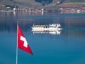 Swiss flag and a tourist boat on the Murtensee lake Royalty Free Stock Photo