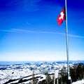 Swiss flag waving in a snowy landscape on top of a mountain