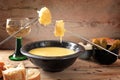 Swiss fondue from melted cheese with bread on long forks, pickles and wine on rustic wooden planks, copy space, selected focus Royalty Free Stock Photo