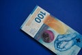 100 Swiss Francs CHF money bills bundle bright color closeup laying on blue clean background