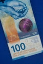 100 Swiss Francs CHF money bills bundle bright color closeup laying stacked up on blue background